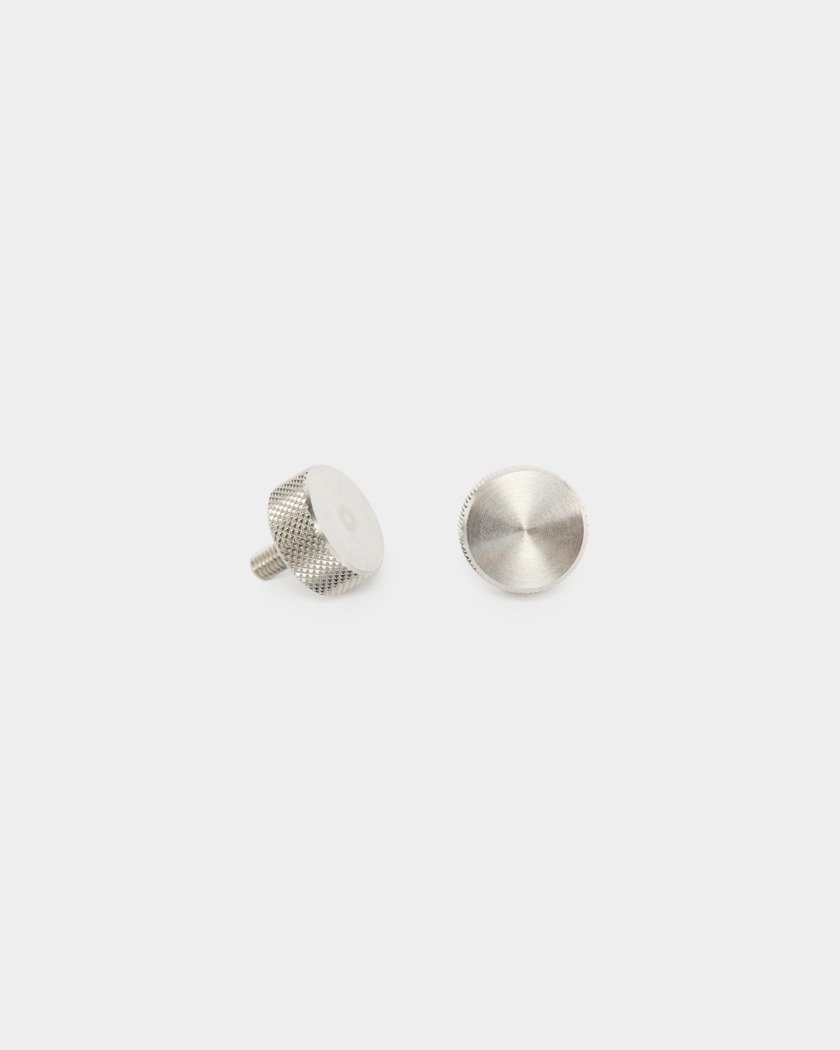 Dois parafusos de aperto manual WoodUpp em aço inoxidável steel (M5x10mm, 20x8.8), acessórios para painéis acústicos Akupanel, apresentados na vertical e na horizontal sobre um fundo branco liso.